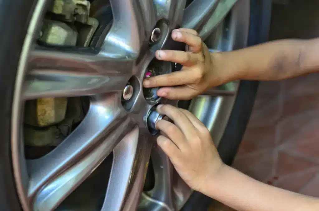 Wheel Maintenance Check by Premier Auto Works in New Oxford, PA: Close-up of hands tightening lug nuts on a car wheel, emphasizing the importance of secure wheel bolts to prevent damage and ensure safety.