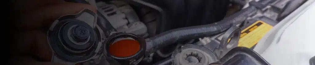 Preventative maintenance for cars and trucks in New Oxford, PA with Premier Auto Works, INC. Person checking the red coolant level inside a car engine's radiator.