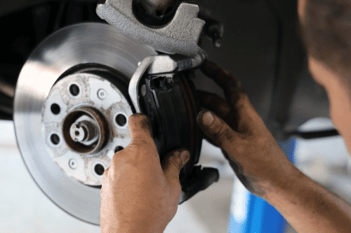 Brake repair in New Oxford, PA with Premier Auto Works. Close-up of a mechanic's hands installing a brake pad on a car's disc brake rotor.