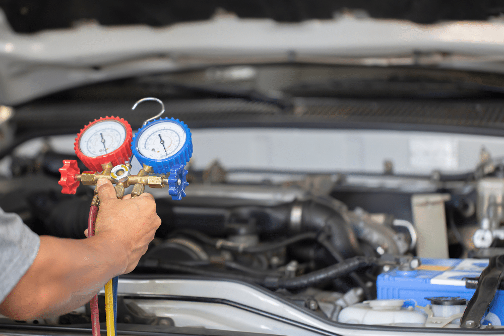 a/c service, Auto repair in New Oxford, PA at Premier Auto Works Inc. Technician using HVAC manifold gauge set to check a vehicle’s air conditioning system with the hood open.